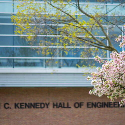 John C. Kennedy Hall of Engineering with spring flowering trees on right